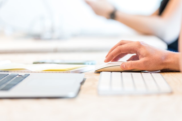 Close up of someone using a laptop with an external white mouse and keyboard